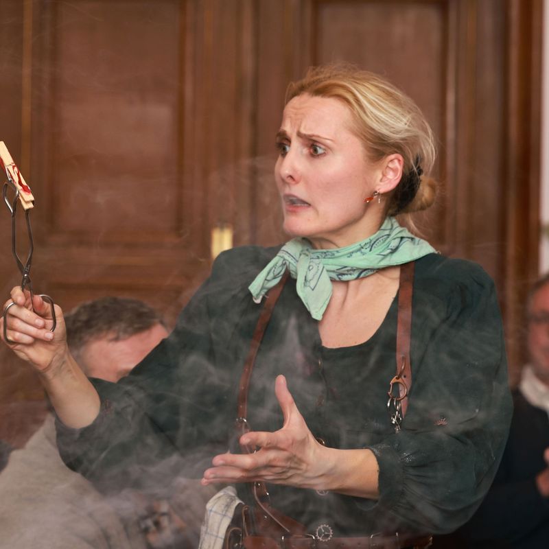 Verrückte Erfinderin hält blutige Wäscheklammer mit einer Grillzange und Nebel
