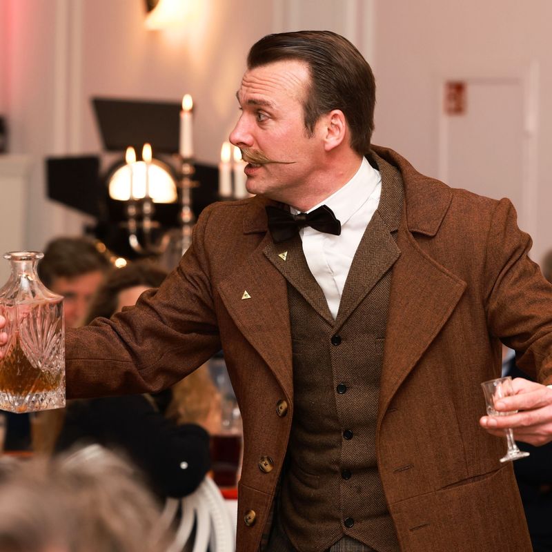 Conan Doyle mit Sherryflasche und Glas gestekulierend