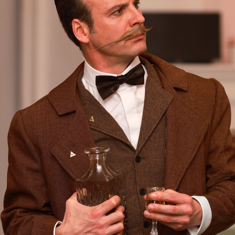 Conan Doyle hält sich an Sherryglas und Flasche fest